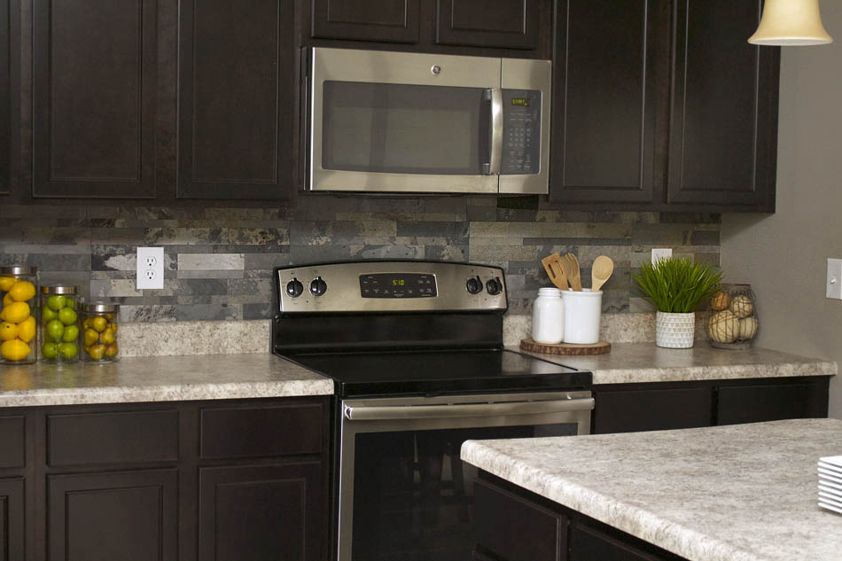 The kitchen with the faux stone put up and fruit in jars in front of it.