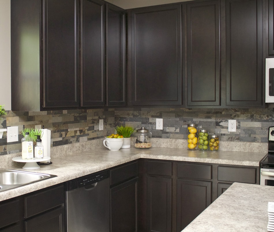 The multicoloured of grey, beige, white faux stone in kitchen with dark cabinets.