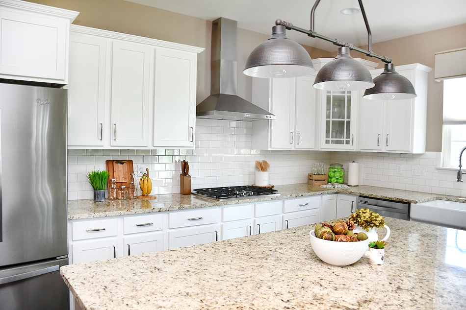 The white kitchen with a cutting board on the counter and a bowl of fruit.