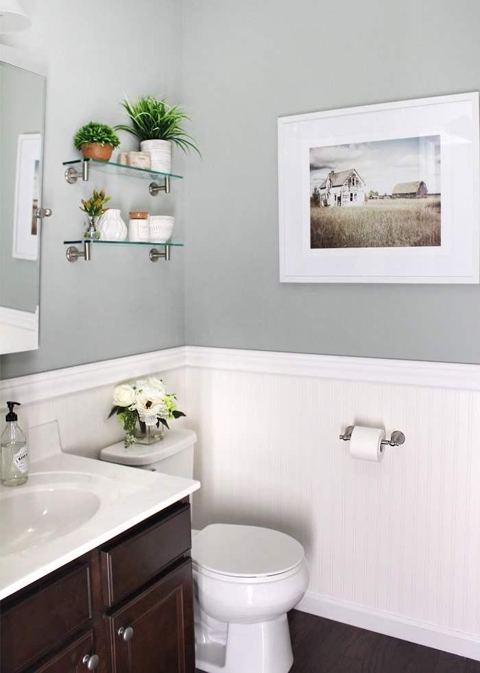 A white toilet in the bathroom with flowers on the toilet.