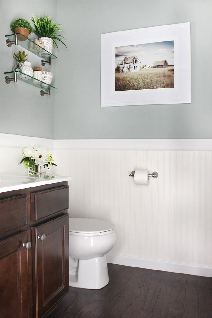 A small bathroom with wallpaper and a picture on the wall.