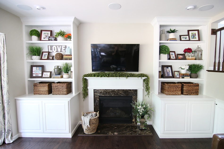 A fireplace flanked by two built ins and collectibles on the shelves.