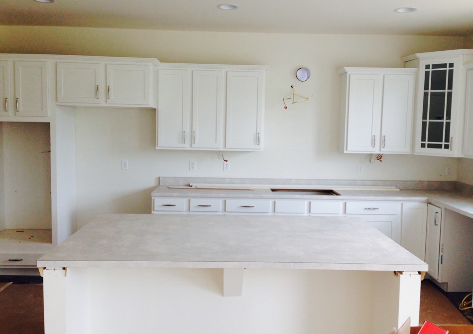 A plain white kitchen with empty shelves and island.