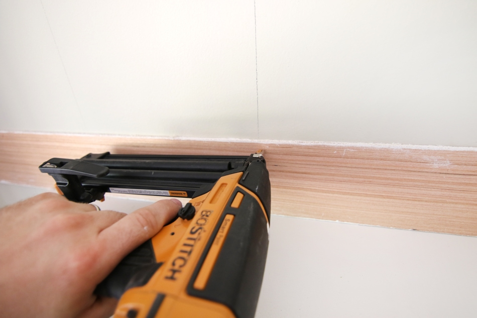 Using a staple gun to put up the board on the wall.