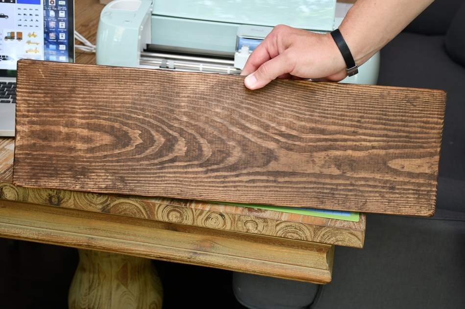 Holding the stained wood upright on a table.