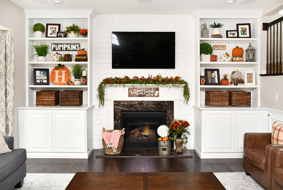 The all white bookshelves and fireplace with a tv above it.