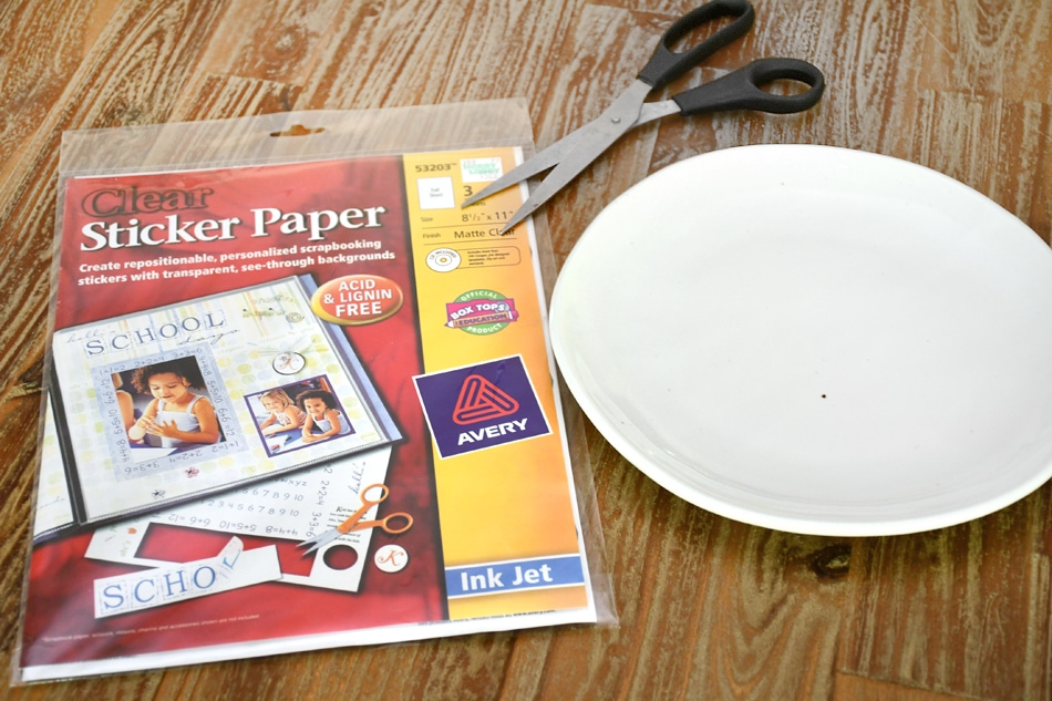 A white plate, stickers and scissors on a table.