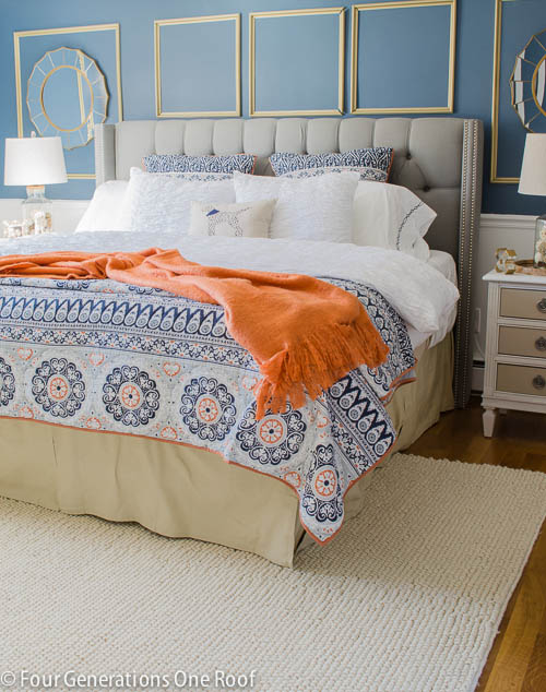 Blue walls and blue and orange blankets in bedroom.