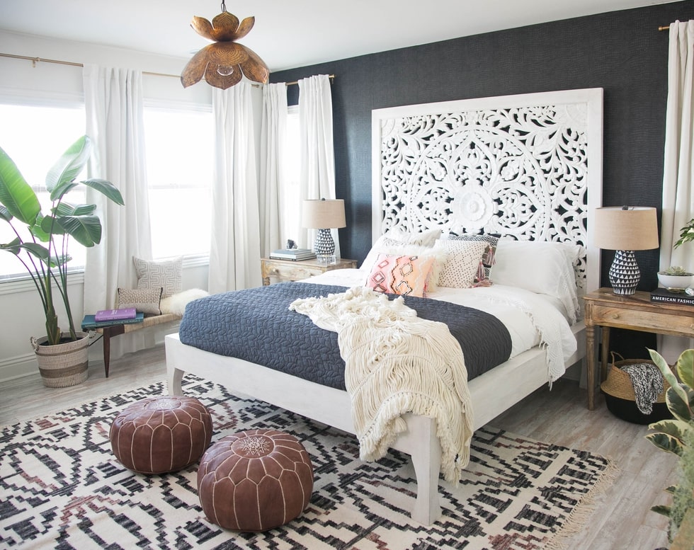 Black wall with a white headboard and black and white rug on bedroom.