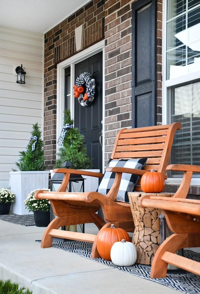 Two Adirondack chairs on the front porch with pumpkins.