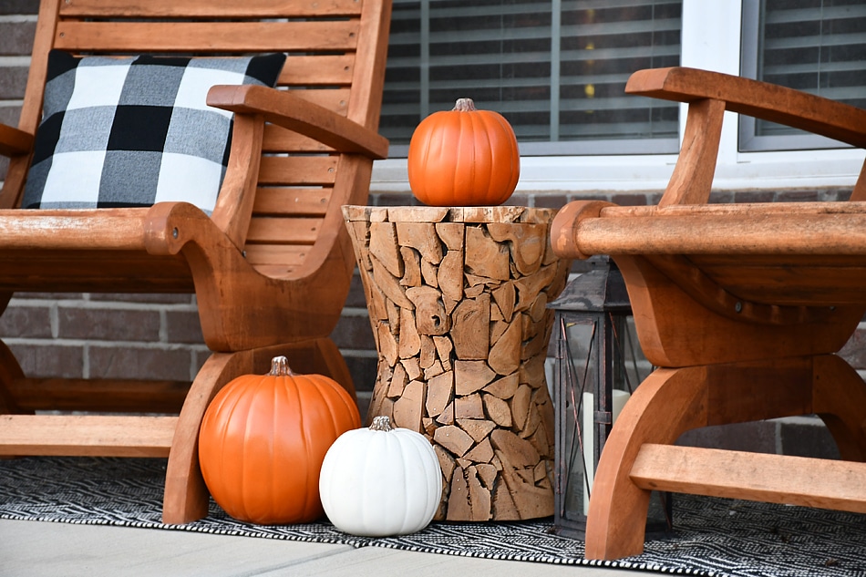 Wooden side table with a pumpkin on it on the front porch.