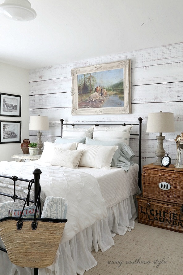 Shiplap wall with steel frame black bed and white bedding in master bedroom.