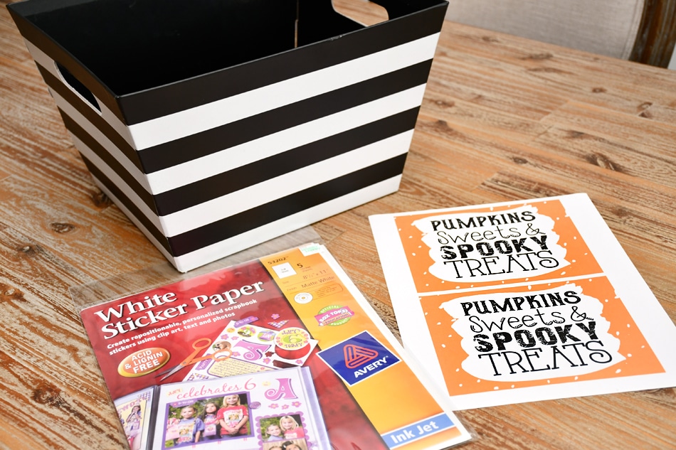 Black and white striped container, pumpkin stickers lying beside it on the table.