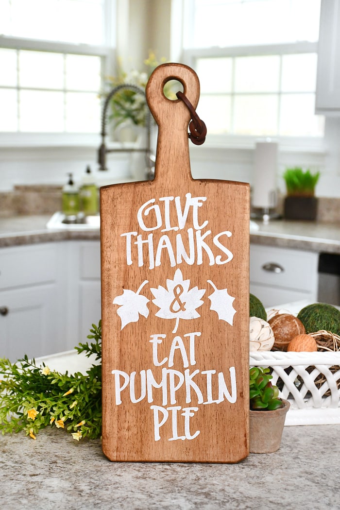 The stenciled cutting board standing up on the counter.