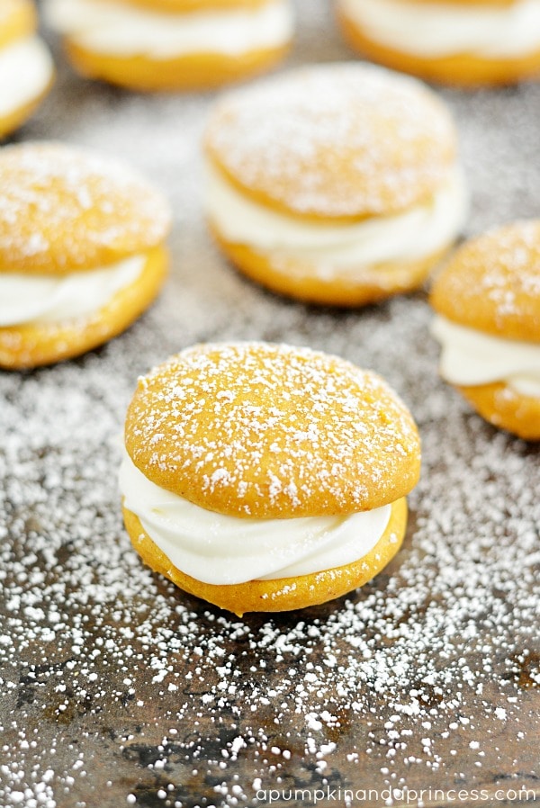 Whoopie pies made of pumpkin on a tray with icing sugar on top.