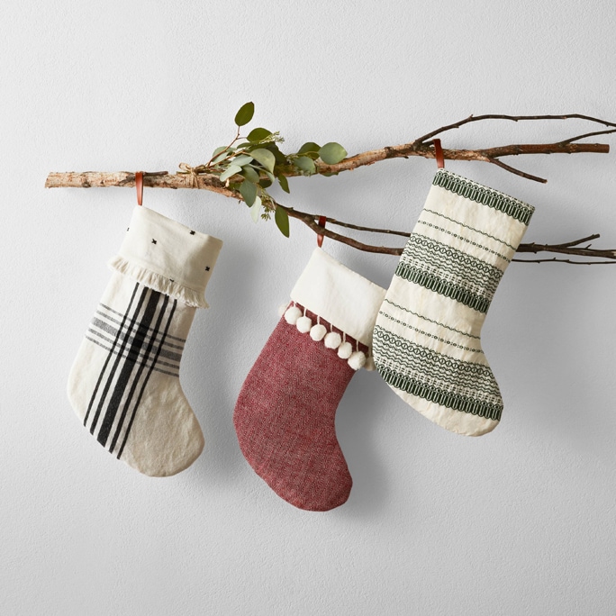 Black and white, and red stocking hanging on a branch.