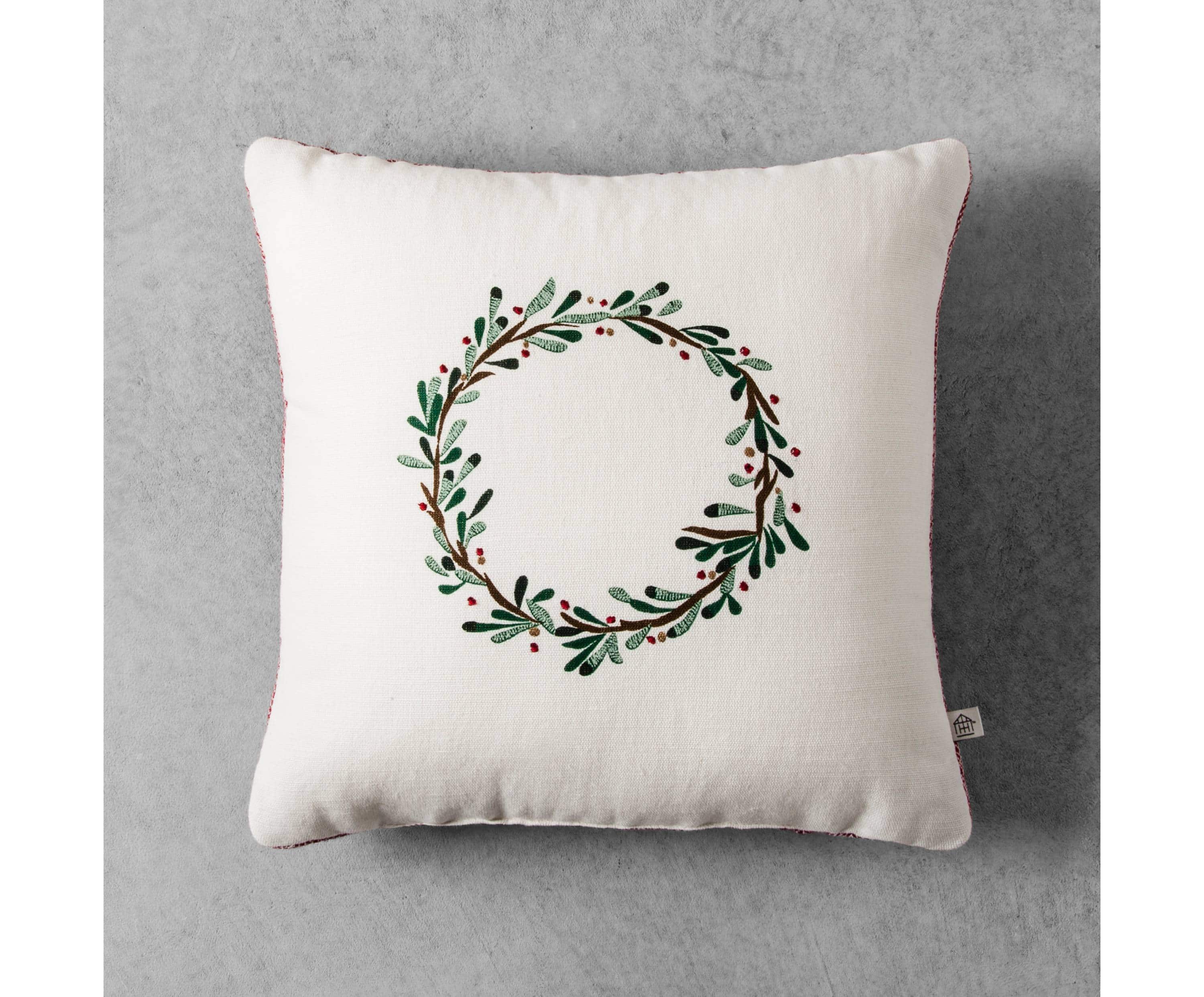 A white pillow with a green wreath motif on it.