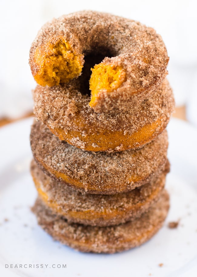 Donuts with pumpkin stacked on top five high with a bite taken out of the top one.