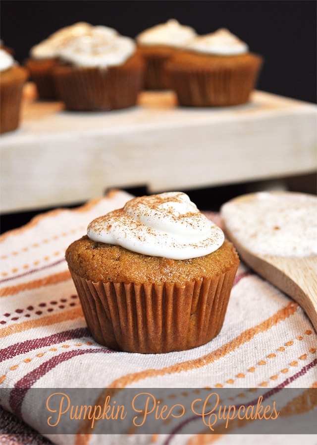 Pumpkin pie cupcake that is iced with cinnamon on top, on the counter.