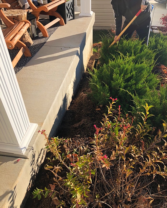 Person with a shovel digging the soil away from the foundation.