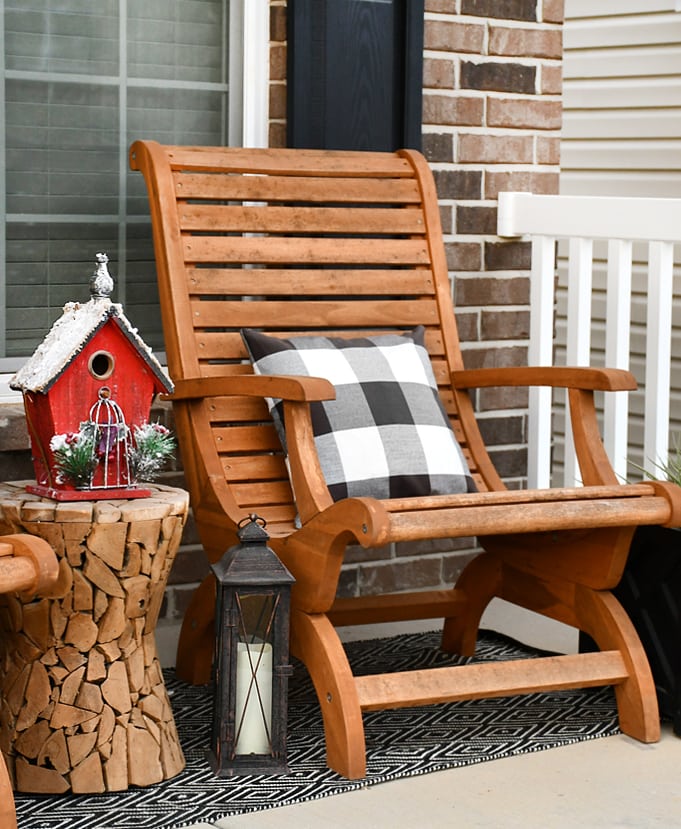 Christmas front porch decorations with an Adirondack chair. a checked pillow on it and a little bird house beside it.