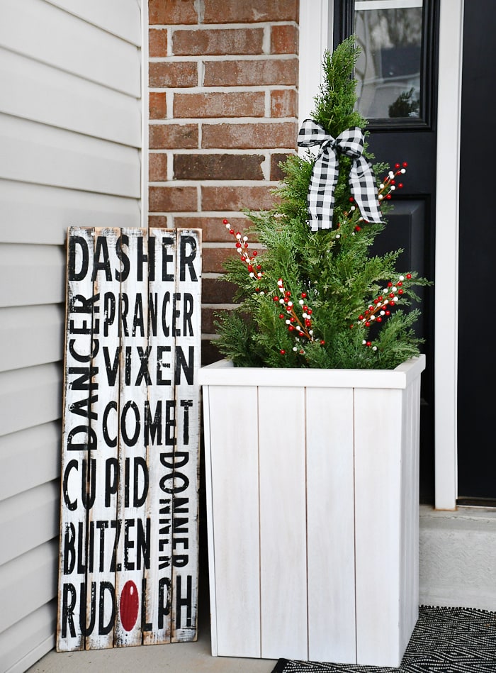 A Christmas sign beside the planter, and a decorated topiary.