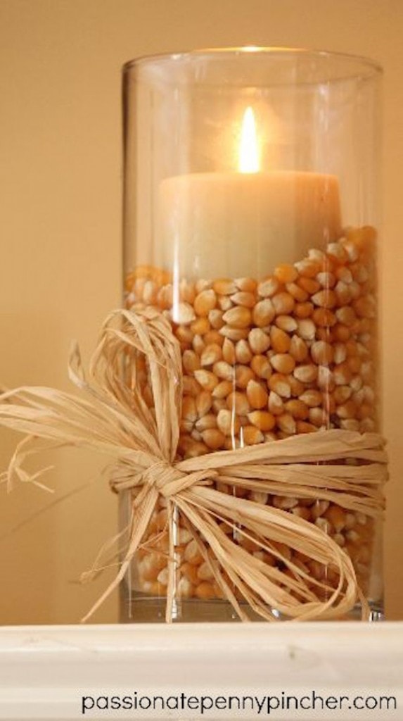 Popcorn kernels in a glass vase with a candle on top and sisal rope tied around the base in a bow.