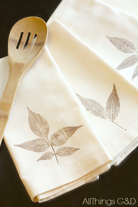 Leaves stamped on a white napkin with a wooden ladle laying on top.