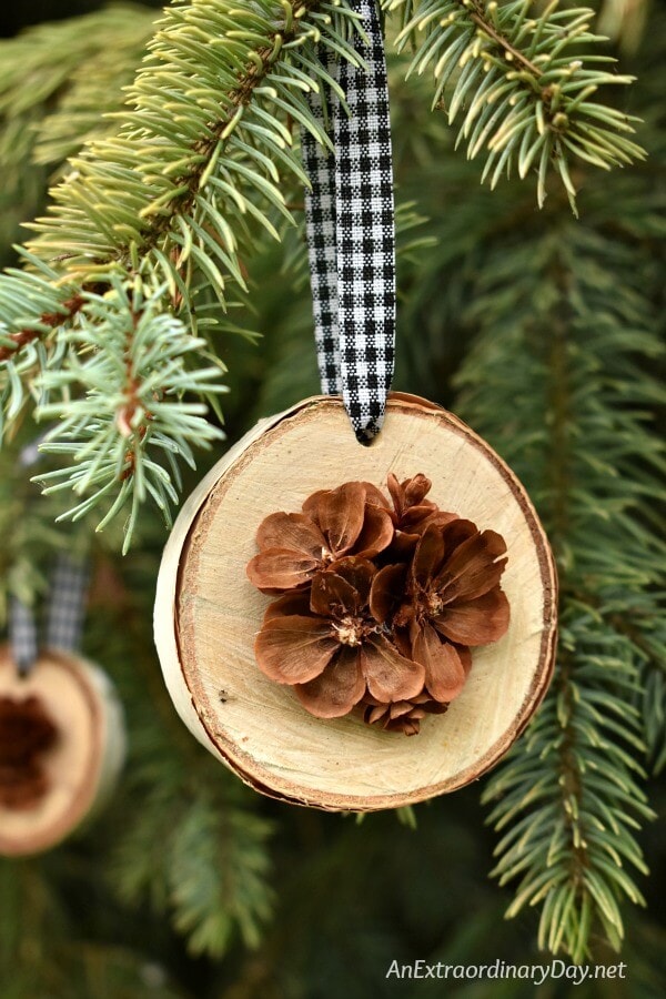 A wooden ornament with light brown wooden flowers hanging on the Christmas tree.