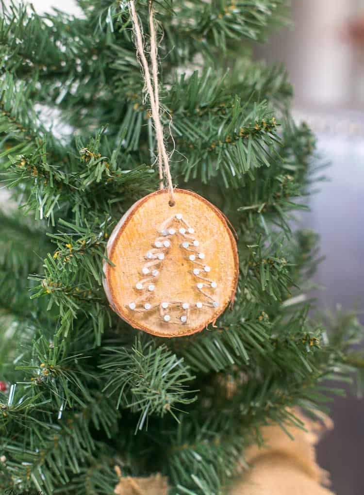 A wooden ornament with a simple Christmas tree on it.