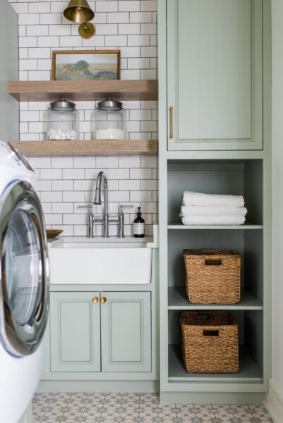 Sherwin Williams Oyster Bay painted cabinets in a laundry room with white washer and dryer and white farmhouse sink